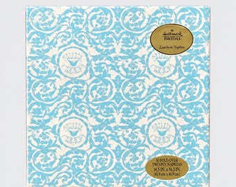May include: A square package of 30 fold-over two-ply Hallmark Bridal luncheon napkins measuring 16.5 inches by 16.5 inches. The packaging features a light blue and white repeating damask pattern with circular crown motifs throughout the design.