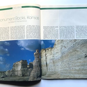 May include: Monument Rocks, Kansas, a natural landmark, features towering white chalk formations against a blue sky with fluffy clouds. The rocks are a unique geological formation, a remnant of the ancient inland sea.