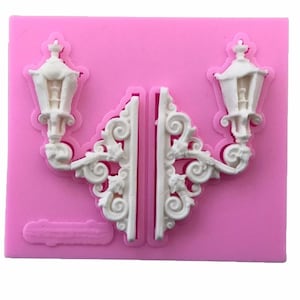 May include: A pink silicone mold for baking or crafting. The mold features two ornate lamppost designs with intricate details.