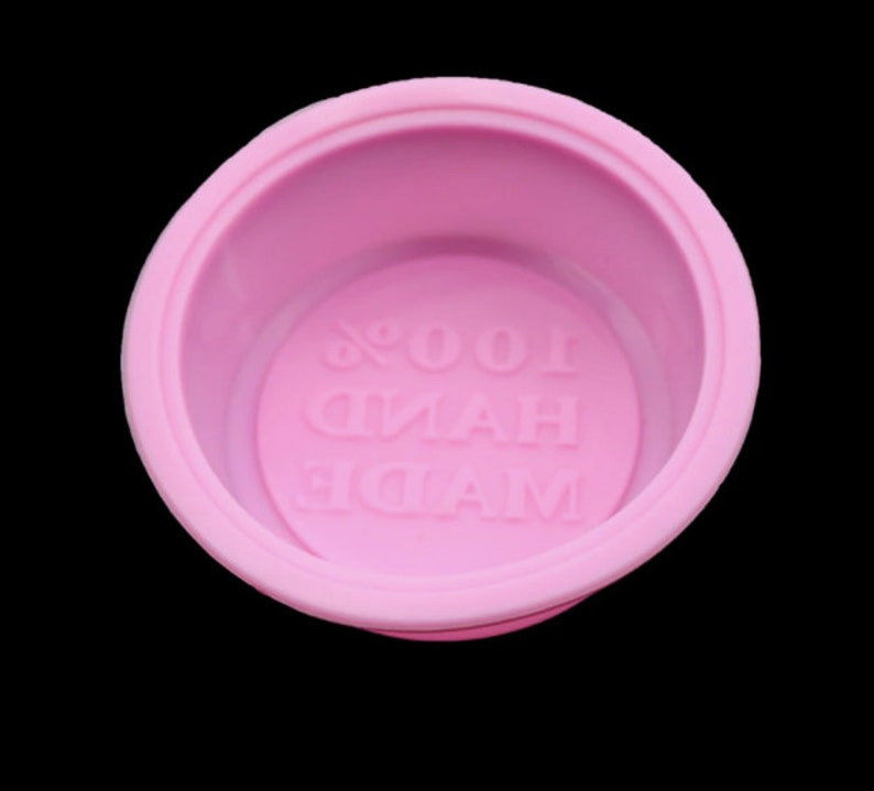 Puede incluir: Molde de silicona rosa con el texto "MADE HAND 100%" en relieve en la parte inferior.