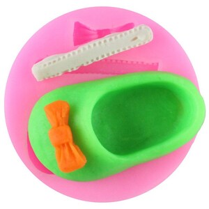 May include: Silicone mold for making a green shoe with an orange bow. The mold also includes a separate mold for making a white bow.