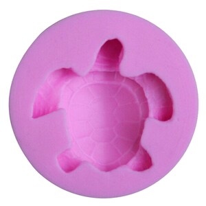 May include: Pink silicone mould shaped like a turtle. The mould is designed to create a turtle-shaped cake or other edible item.