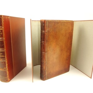 Op de afbeelding: Een bruin lederen gebonden boek met de titel "Life of Richard Nash" en de auteur "Oliver Goldsmith" op de rug. Het boek is open om de binnenpagina's te laten zien.