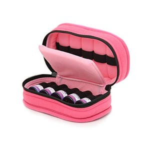 May include: Pink zippered travel case with a soft, pink interior and multiple slots for holding small bottles. The case is open and filled with small bottles.
