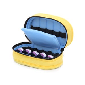 May include: Yellow felt carrying case with a blue felt lining and zipper closure. The case is open and contains eight small glass bottles with purple liquid.