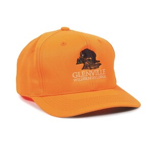 May include: Bright orange baseball cap with a curved brim. The cap features a black and white graphic of a bear and trees, with the text "Glenville Wilderness Lodge" in white lettering.