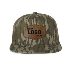 May include: A camouflage-patterned baseball cap with a flat brim. The cap features a brown leather patch with the text "Your LOGO here" in black and blue. The hat is designed with a classic six-panel construction.