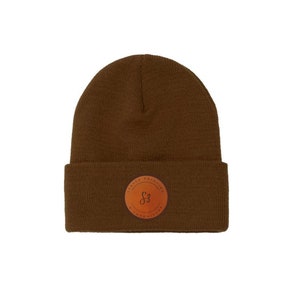 May include: A brown knit beanie with a brown leather patch featuring the text "The Local Founder" and a stylized "S3" logo.