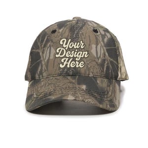 May include: A camouflage baseball cap with the text "Your Design Here" in a stylized font. The cap features a curved brim and a distressed look, with a pattern of brown, green, and black.