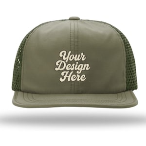 May include: An olive green trucker hat featuring a structured front panel and a breathable mesh back. The front displays the text Your Design Here in a cream-colored, cursive font. The cap includes a flat brim and a matching olive green button.