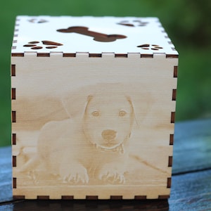 May include: A wooden tissue box with a laser-engraved image of a dog and paw prints. The top of the box has a cut-out bone shape.