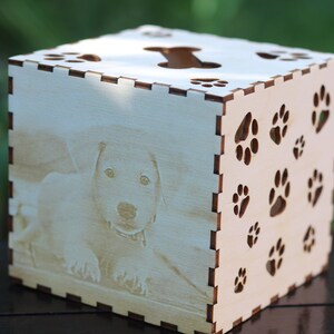 May include: A wooden tissue box with a cutout of a dog bone on the top and paw prints on the sides. The box has a photo of a dog on the front.
