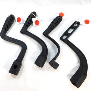 May include: Four black cast iron handles with different designs. The handles are all in good condition and have a smooth finish.
