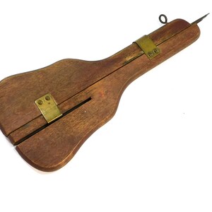 May include: A vintage wooden tool with a dark brown finish. It features a long, curved handle and a metal blade. Brass hardware secures the wooden components. A small metal ring is attached to the top.