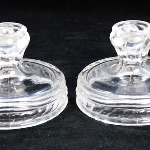 May include: Two clear glass candle holders with a textured base and a fluted top.