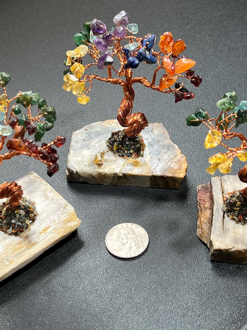 Peut inclure: Trois petits arbres en fil de fer enroul&eacute; avec des pierres pr&eacute;cieuses color&eacute;es sur chaque branche. Les arbres sont sur de petites bases en pierre plates, grises et blanches. Une pi&egrave;ce de monnaie am&eacute;ricaine de 25 cents est repr&eacute;sent&eacute;e &agrave; titre de comparaison.
