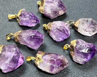 Könnte beinhalten: Sieben Amethyst-Kristall-Anhänger mit vergoldeten Einstellungen. Die Kristalle sind in verschiedenen Formen und Größen, mit einer violetten und klaren Farbe.