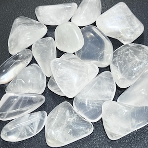 May include: A collection of smooth, white tumbled stones. The stones are various shapes and sizes, with a translucent, milky white appearance.