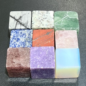 Puede incluir: Nueve piedras preciosas cuadradas en varios colores y patrones. La colección incluye blanco con vetas negras, blanco moteado, verde, azul con motas blancas, rojo, rosa, rojo oscuro, morado y un blanco azulado translúcido. Dispuestas en una cuadrícula 3x3.