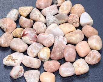 May include: A collection of tumbled pink, white, and brown stones. The stones are smooth and polished, with a variety of patterns and textures.
