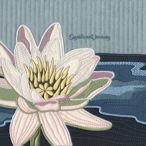 Könnte beinhalten: Eine gestickte weiße Seerose mit rosa und grünen Akzenten auf einem blauen Stoffhintergrund. Der Text "Significant Journey" ist in der oberen rechten Ecke gestickt.