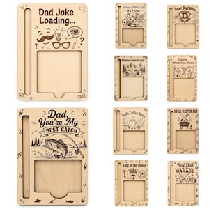 Op de afbeelding: Een verzameling houten bureau-organizers met verschillende gegraveerde ontwerpen. Elke organizer heeft een sleuf voor een telefoon en ruimte voor notities. Ontwerpen zijn onder meer "Dad Joke Loading", "Happy Father's Day" en "Best Dad in the Garage".