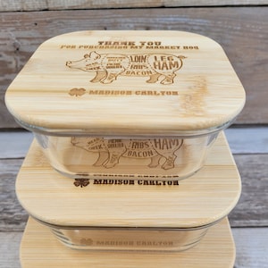 May include: Three stacked bamboo cutting boards with glass containers. The top board has a pig illustration with the text "Thank you for purchasing my market hog" and "Madison Carlton". The middle board has a pig illustration with the text "Madison Carlton". The bottom board has the text "Madison Carlton".