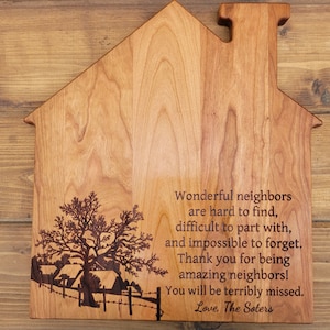 May include: A wooden house-shaped cutting board with a laser-engraved design of a tree and houses. The board has a message engraved on it that reads: "Wonderful neighbors are hard to find, difficult to part with, and impossible to forget. Thank you for being amazing neighbors! You will be terribly missed. Love, The Soters."