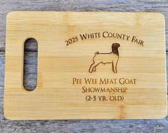 May include: A wooden cutting board with a handle, engraved with the text "2025 White County Fair", "Pee Wee Meat Goat Showmanship (2-5 yr. old)", and a silhouette of a goat.