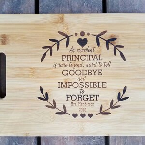 May include: A bamboo cutting board with a laser engraved message that reads "An excellent PRINCIPAL is rare to find, hard to tell GOODBYE and IMPOSSIBLE to FORGET. Mrs. Henderson 2020".