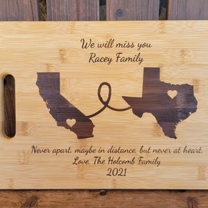May include: A wooden cutting board with a laser-engraved design of the states of California and Texas connected by a heart. The text "We will miss you Racey Family" and "Never apart, maybe in distance, but never at heart. Love. The Holcomb Family 2021" is engraved on the board.