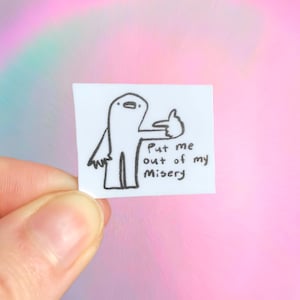 May include: A small, white square with a hand-drawn cartoon figure giving a thumbs-up. The figure is outlined in black, with the text "Put me out of my Misery" below it. The background is a soft blend of pink, purple, and blue.