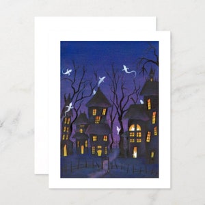 May include: A Halloween-themed greeting card featuring a spooky illustration. The artwork depicts silhouetted haunted houses with glowing windows under a dark blue sky. White ghost figures float among the bare tree branches.
