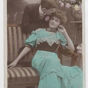 Pocztówka - Dama w niebieskiej sukience na kanapie. Z mężczyzną z tyłu. Opublikowano Belgia 1906 #2047c