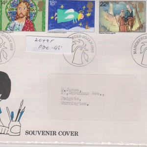 Pode incluir: Envelope de recordação com selos temáticos de Natal e um desenho de um menino a escrever. Os selos retratam o Pai Natal, Jesus, um anjo e os Reis Magos. Carimbo postal de Manchester, 20 de janeiro de 1982.