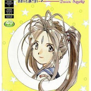 May include: A comic book titled Oh My Goddess! Queen Sayoko, featuring a yellow cover with white stars and a central illustration of a character with long brown hair in a ponytail, wearing a blue and white uniform with a Bell 10 patch.