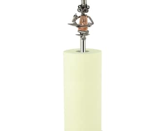 May include: A metal paper towel holder featuring a whimsical figure made of nuts, bolts, and other hardware. The figure is wearing an apron and holding a wrench. The holder is designed to hold a standard roll of paper towels.