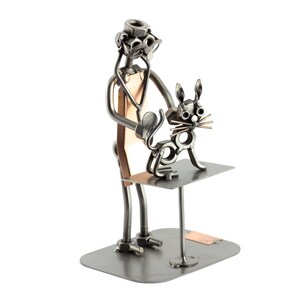 Puede incluir: Una escultura de metal de un veterinario examinando a un gato. El veterinario está hecho de tuercas, tornillos y otras piezas de metal. El gato también está hecho de metal y tiene un estetoscopio alrededor del cuello.