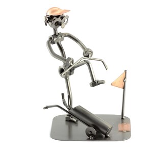 May include: A metal sculpture of a golfer swinging a club, with a golf bag and flag in the background. The sculpture is made of nuts, bolts, and other metal pieces.