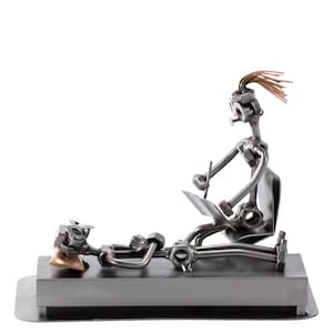 Könnte beinhalten: Eine Metallsculptur, die einen Arzt zeigt, der einen Patienten untersucht. Der Arzt sitzt auf einem Stuhl und hält einen Stift und Papier. Der Patient liegt auf einem Tisch. Die Skulptur besteht aus Muttern, Schrauben und anderen Metallteilen.
