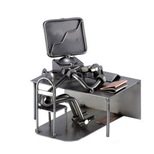 Peut inclure: Sculpture en métal d'une personne assise à un bureau avec un ordinateur, une chaise et un dossier sur le bureau. La sculpture est faite de noix, de boulons et d'autres pièces métalliques.