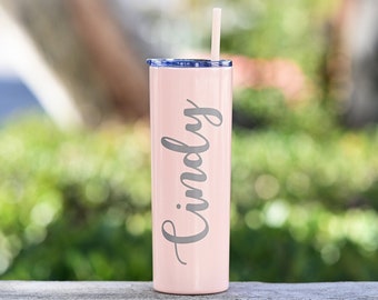 May include: A pink stainless steel tumbler with a straw and the name "Cindy" engraved on the side.