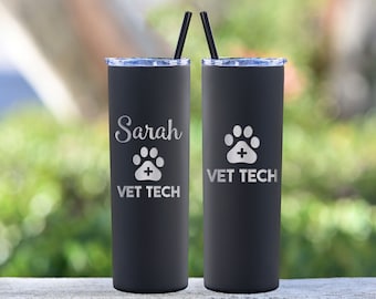 May include: Two black stainless steel tumblers with a paw print and cross design. One tumbler is engraved with "Sarah Vet Tech" and the other with "Vet Tech".