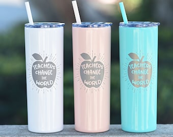 May include: Three stainless steel tumblers with lids and straws. The tumblers are white, pink, and turquoise. Each tumbler has a gray apple design with the text "Teachers Change the World".