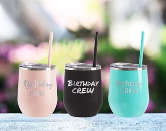 May include: Three stainless steel wine tumblers with lids and straws. The tumblers are pink, black, and turquoise. Each tumbler has the text "Birthday Crew" printed on the side.