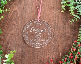 May include: Clear acrylic Christmas ornament with the word "Engaged" and the names Chris & Rebecca and the year 2024.