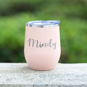 Puede incluir: Un vaso de vino de acero inoxidable rosa con una tapa azul y el nombre "Mindy" grabado en el lateral.