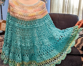 May include: A crocheted shawl with a light blue, green, and yellow color scheme. The shawl has a scalloped edge and a delicate, lacy pattern.