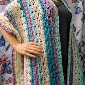 Puede incluir: Un chal de ganchillo multicolor con rayas de color turquesa, morado, rosa y crema.