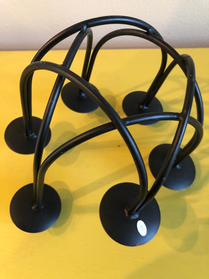 Puede incluir: Un portavelas de metal negro con un dise&ntilde;o &uacute;nico e entrelazado. El portavelas presenta seis bases circulares y varillas met&aacute;licas curvas e intersecantes. Dise&ntilde;ado para m&uacute;ltiples velas, es adecuado para la decoraci&oacute;n del hogar.